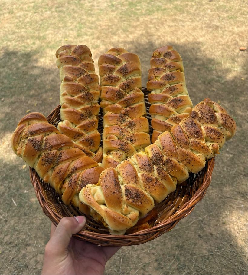 A wicker basket of golden braided breads dusted with herbs