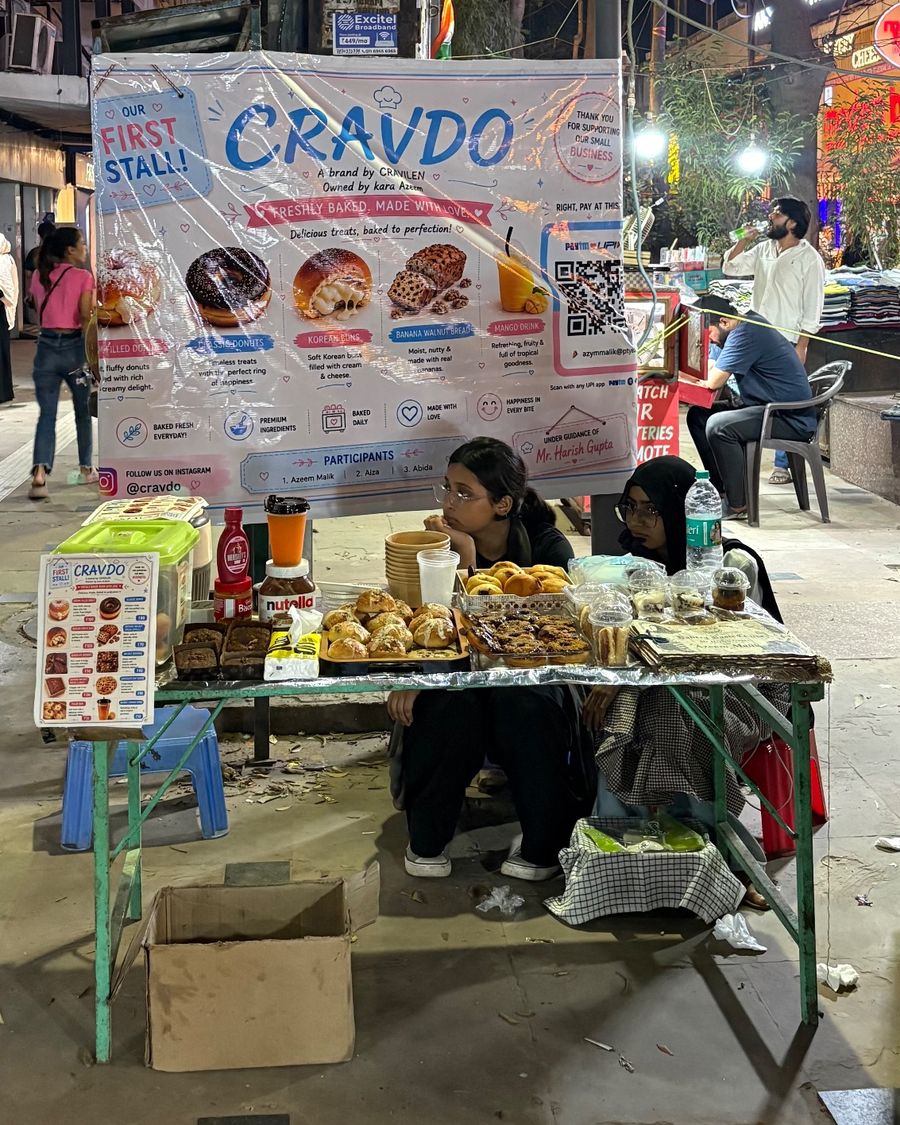 The Cravdo first stall in the evening, with the banner, a menu card and trays of fresh bakes on a green folding table
